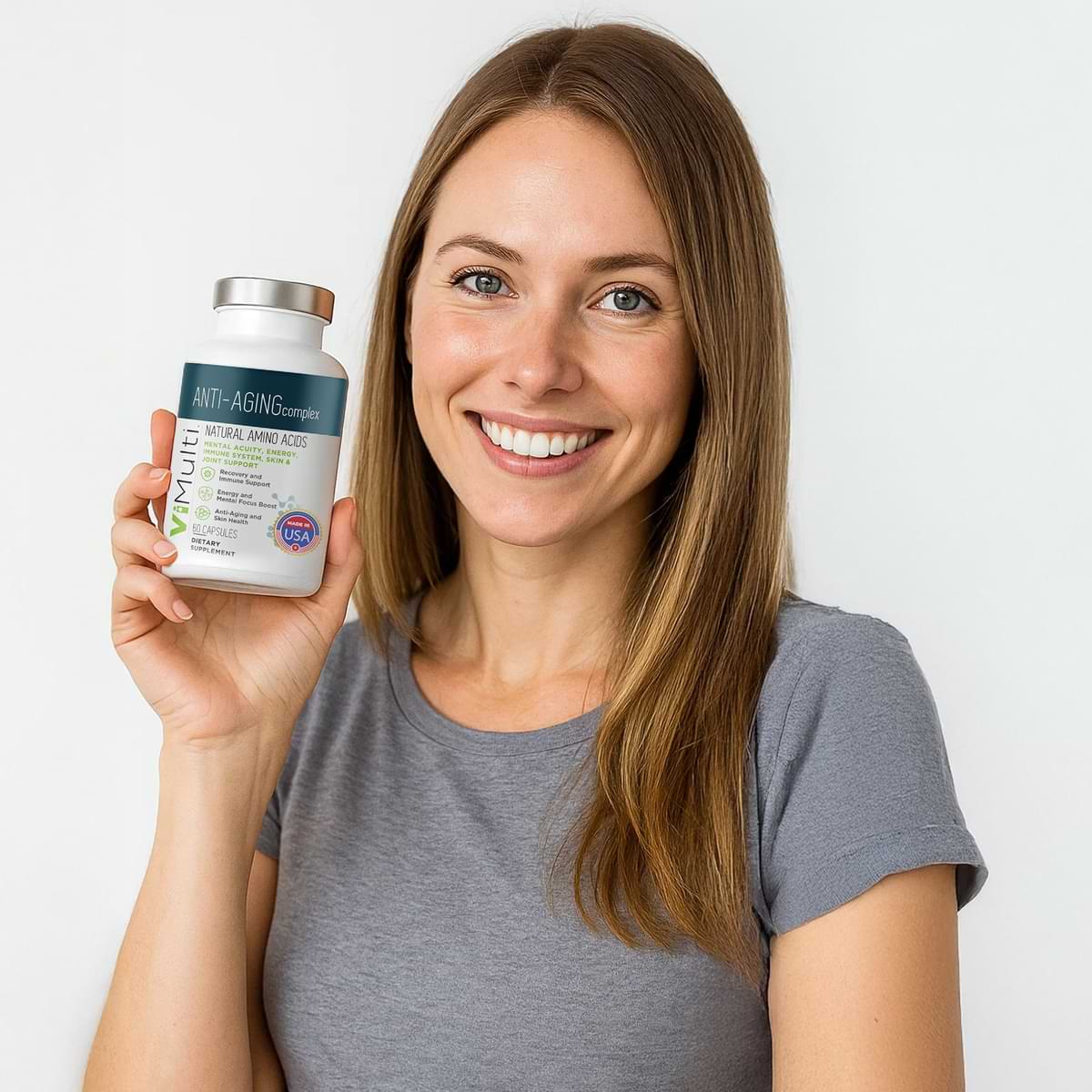 Woman holding a supplement bottle with a plain background